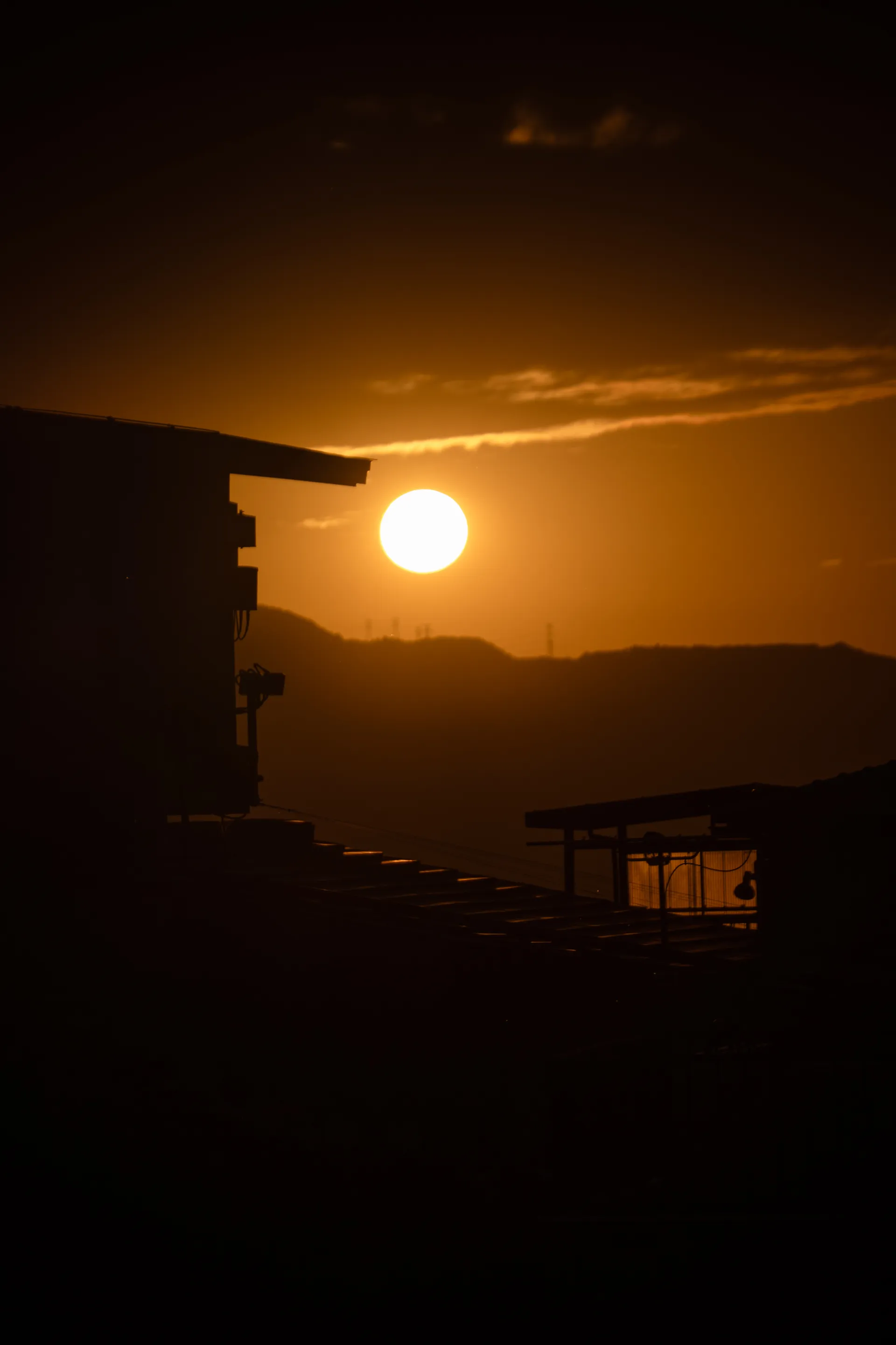 The sun sets perfectly beside a building silhouette, casting warm golden light across the urban landscape.