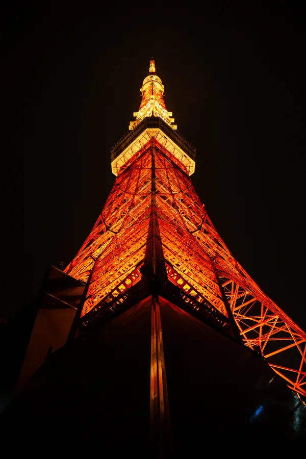 Tokyo Tower blazes orange against the night sky, its lattice structure catching the light.