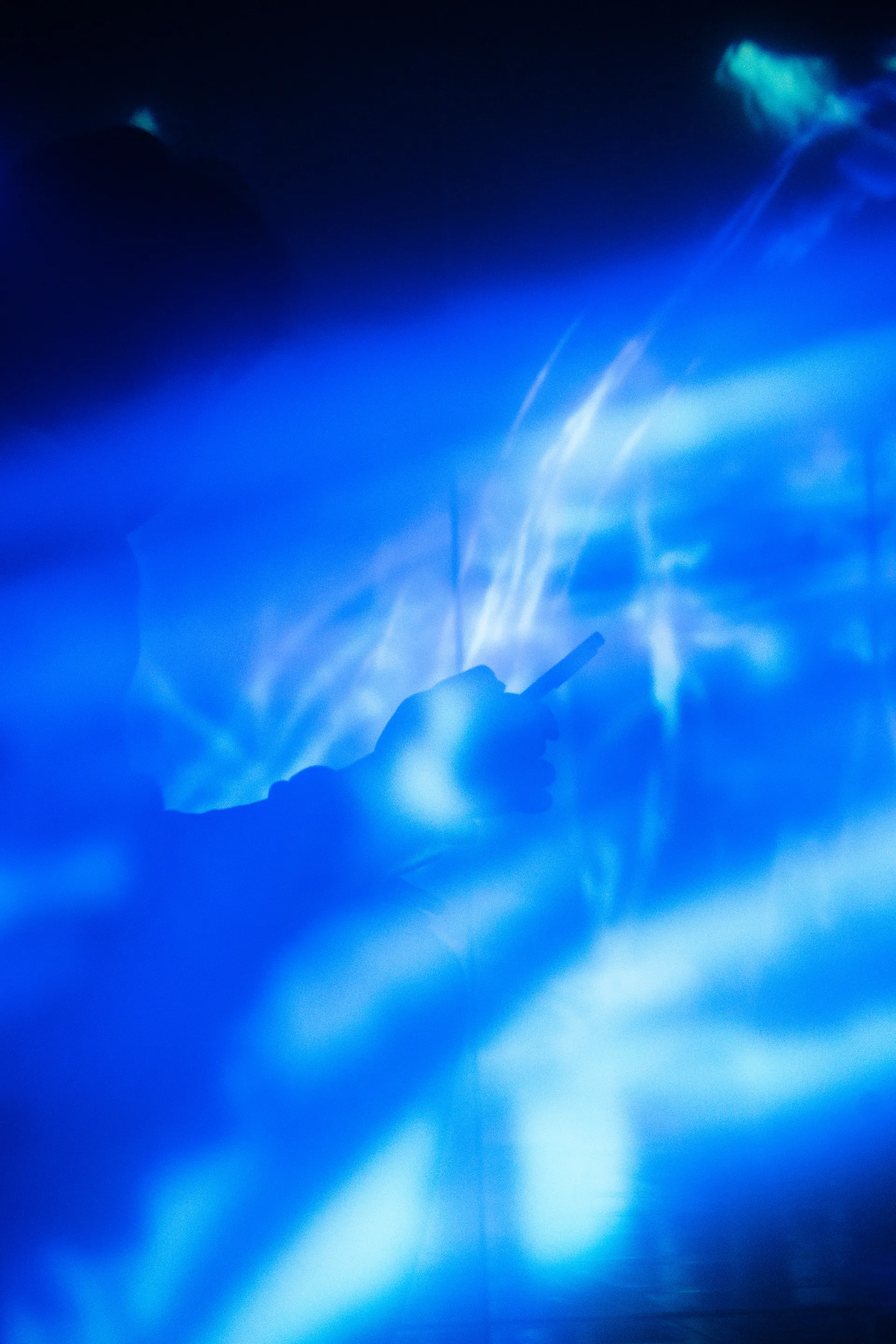 Ethereal blue smoke swirls and glows against darkness, creating an otherworldly abstract composition.