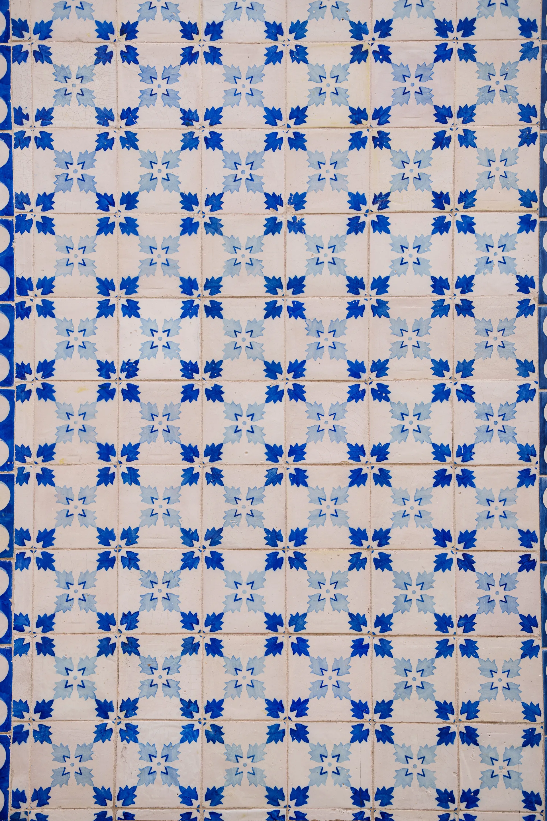 A wall of blue-and-white Portuguese azulejo tiles forms a repeating geometric floral pattern.