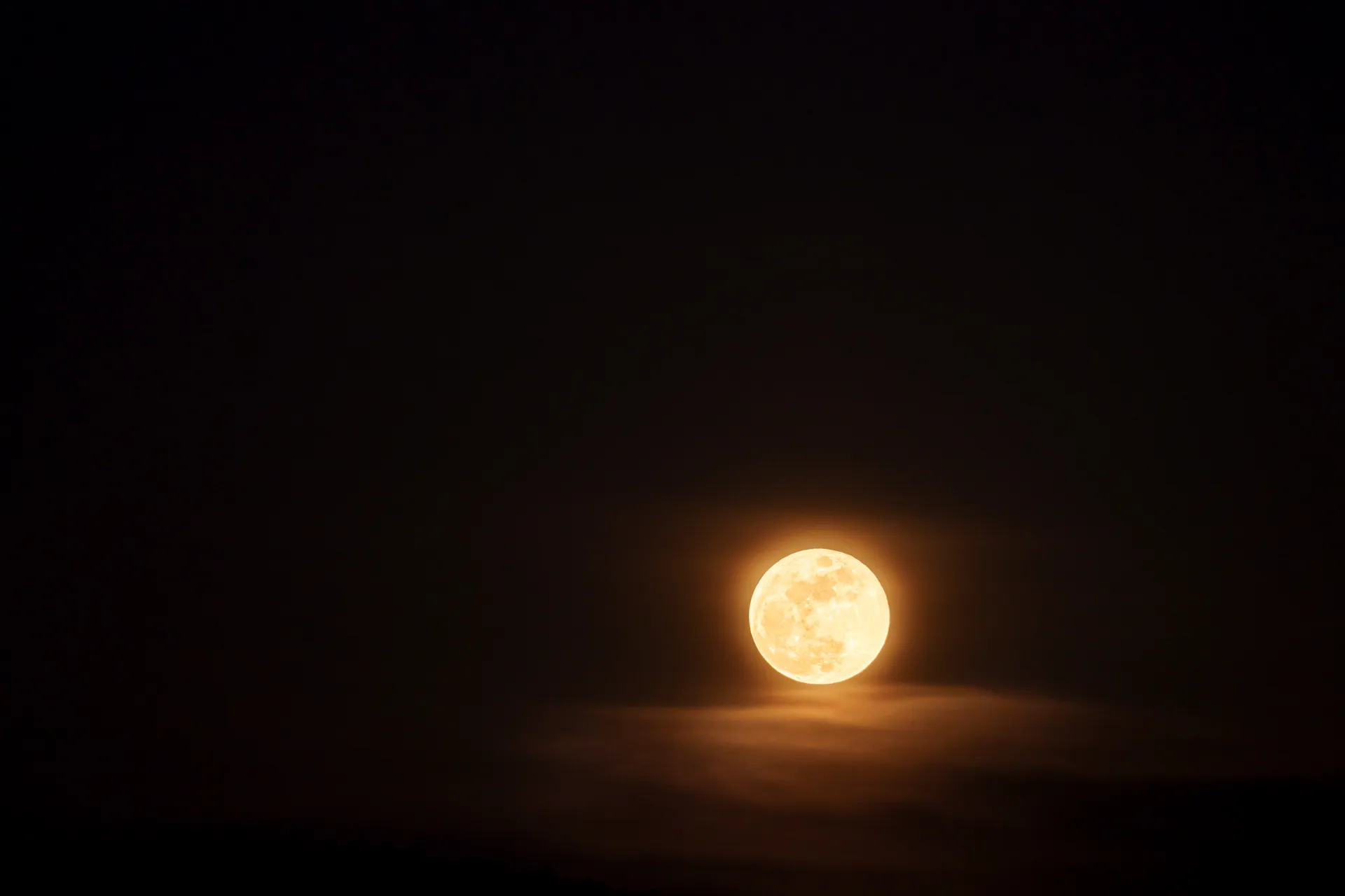 A full moon emerges through soft clouds over Mythenquai, glowing warm against the dark sky.