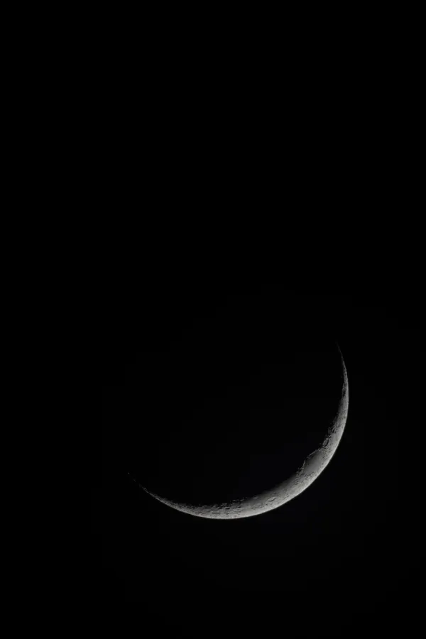 A sliver of moon against the void.
