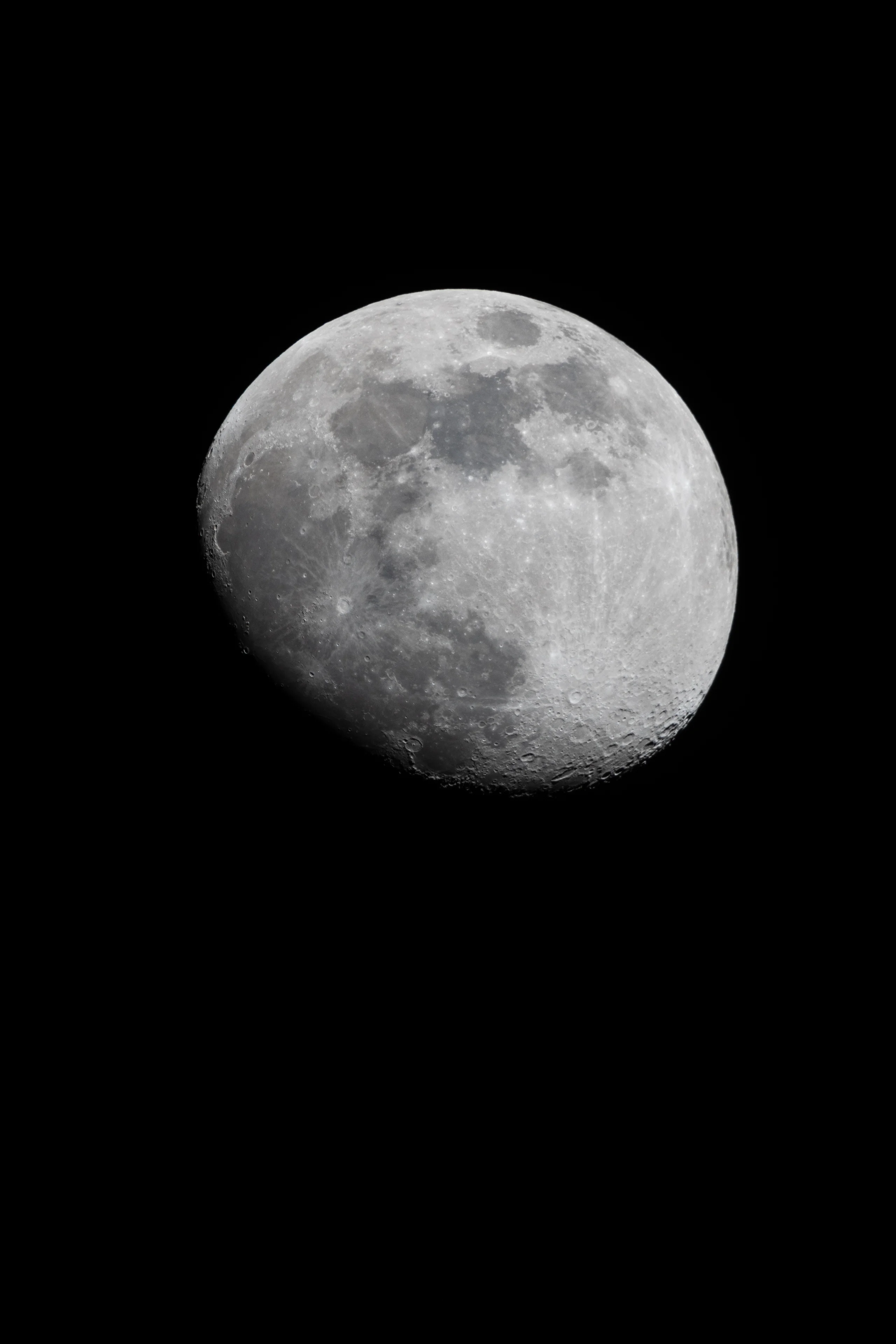 The moon hangs in the black night sky, its craters and maria sharply detailed across the illuminated surface.