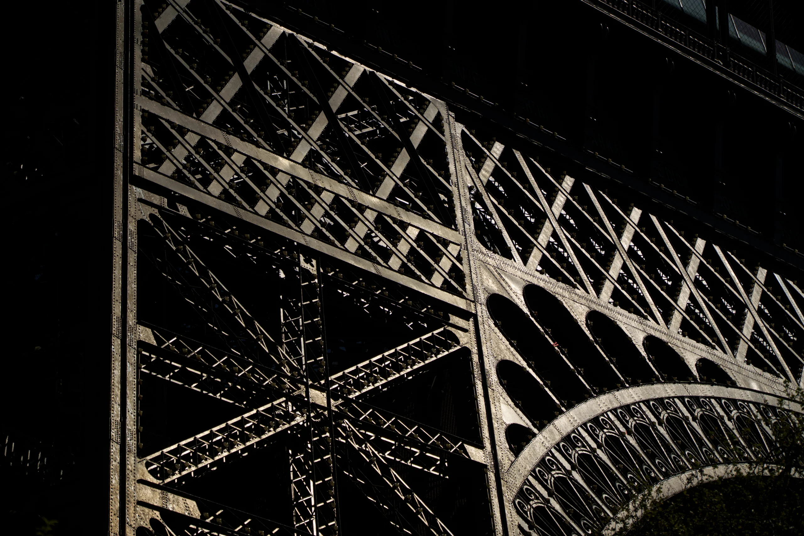 The Eiffel Tower's iron lattice catches low light, revealing the intricate geometry of its riveted arches.